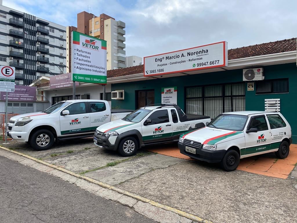 Vista frontal do escritório da Vetor Soluções Construtivas (Engº Márcio Noronha, CREA-RS) e frota caracterizada (Chevrolet S10, Fiat Strada, Fiat Uno) em Novo Hamburgo, Rio Grande do Sul. Serviços de reformas, telhados, alpinismo industrial e laudos técnicos.